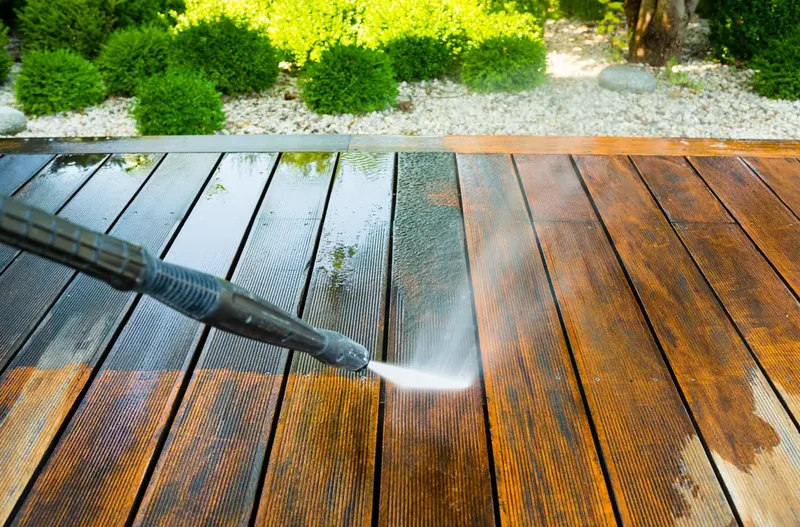 Power washing a wooden deck, half cleaned